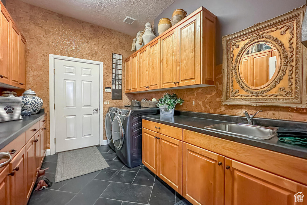 Washroom featuring cabinets, dark tile floors, sink, a textured ceiling, and separate washer and dryer