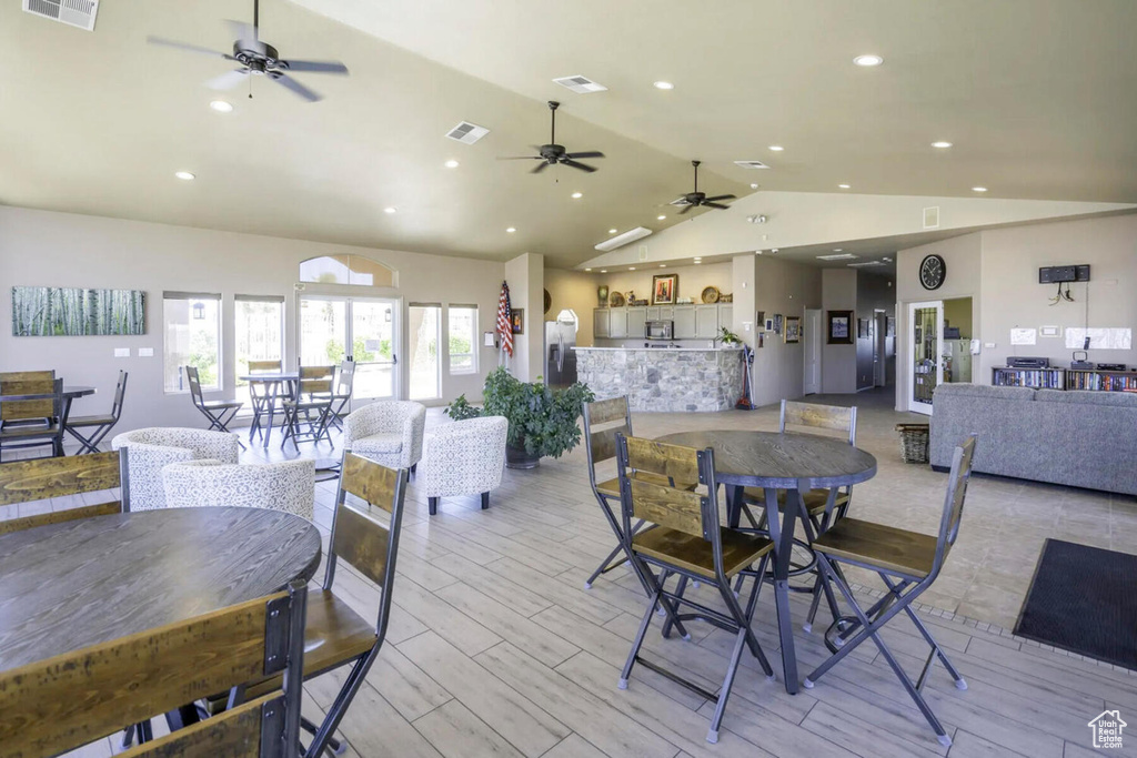 Dining space with high vaulted ceiling, light hardwood / wood-style floors, and ceiling fan