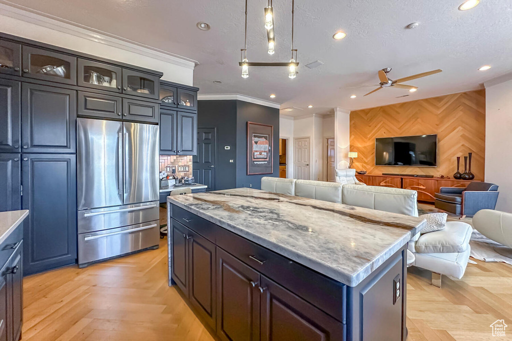 Kitchen featuring ceiling fan, stainless steel refrigerator, a kitchen island, and light parquet flooring