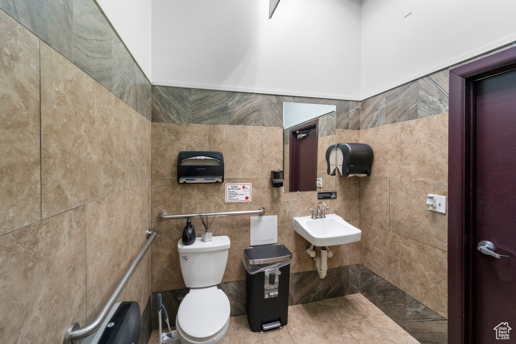 Bathroom featuring sink, tile walls, toilet, and tile floors