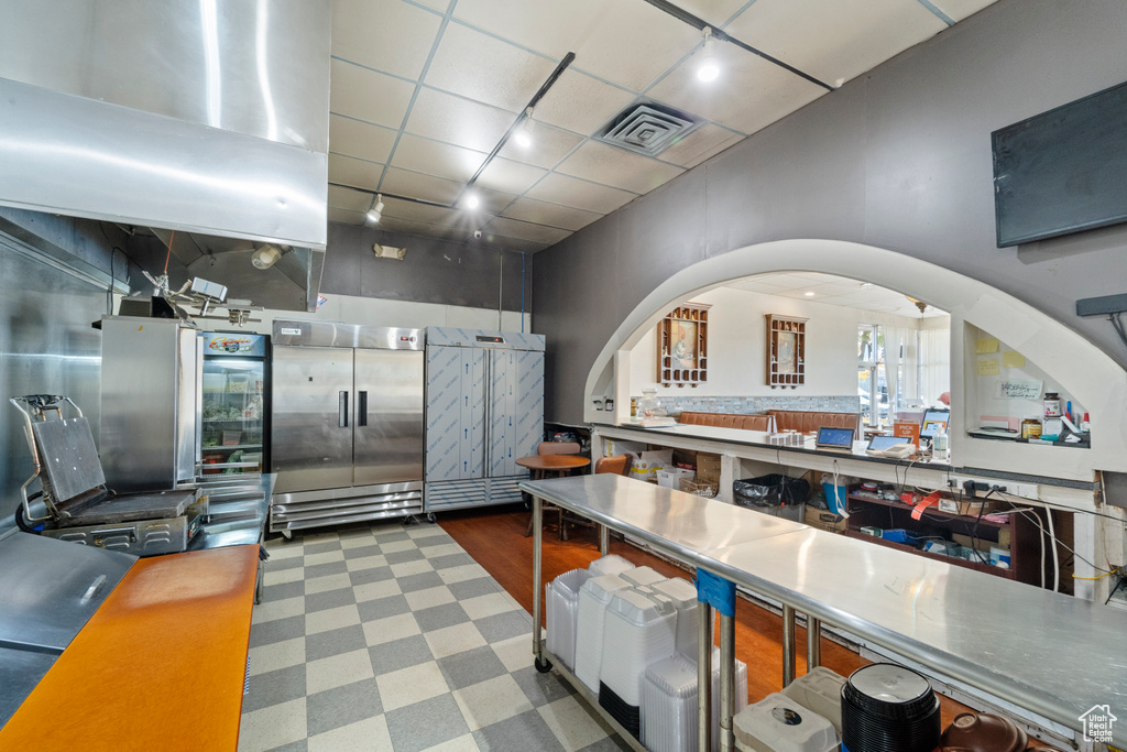 Kitchen featuring stainless steel built in fridge, stainless steel counters, and a paneled ceiling
