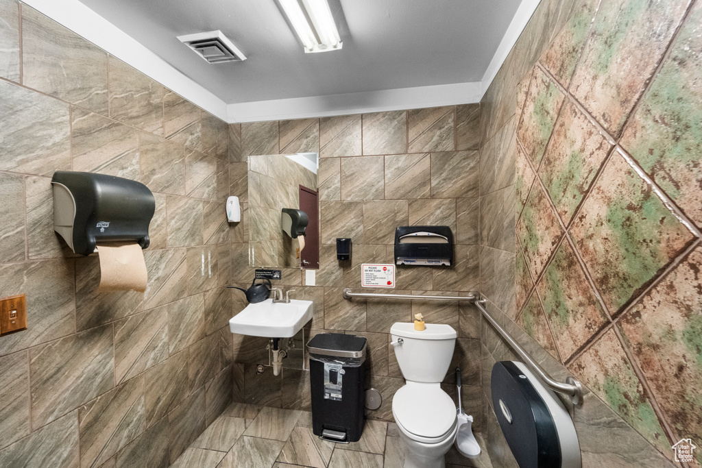 Bathroom featuring sink, toilet, tile walls, and tile flooring