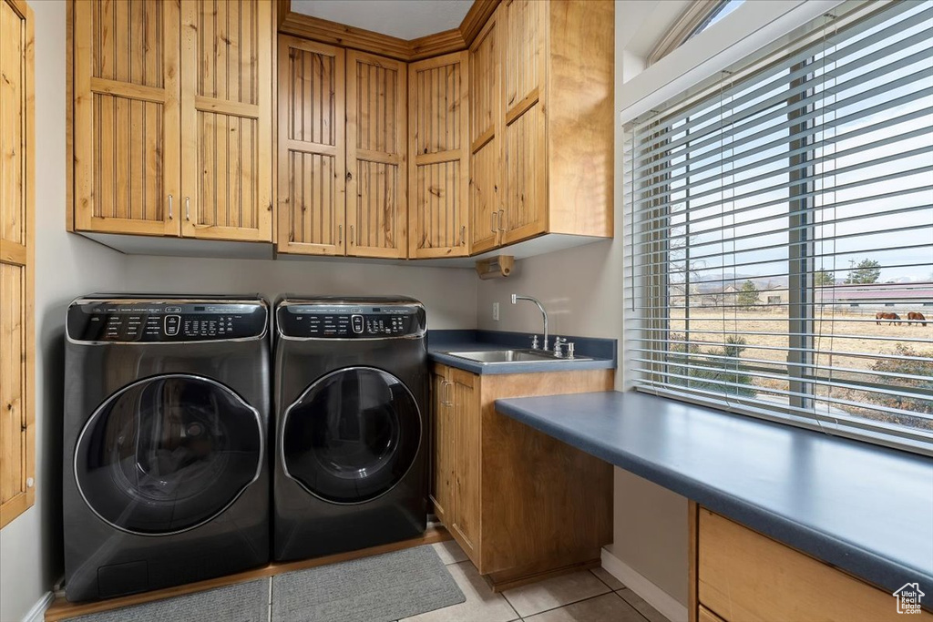 Laundry area featuring plenty of natural light, washer and clothes dryer, light tile floors, and cabinets