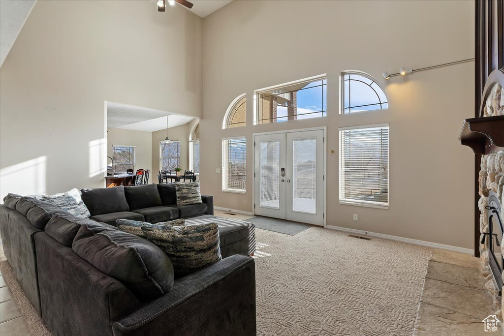 Living room featuring a towering ceiling, french doors, light tile floors, and ceiling fan