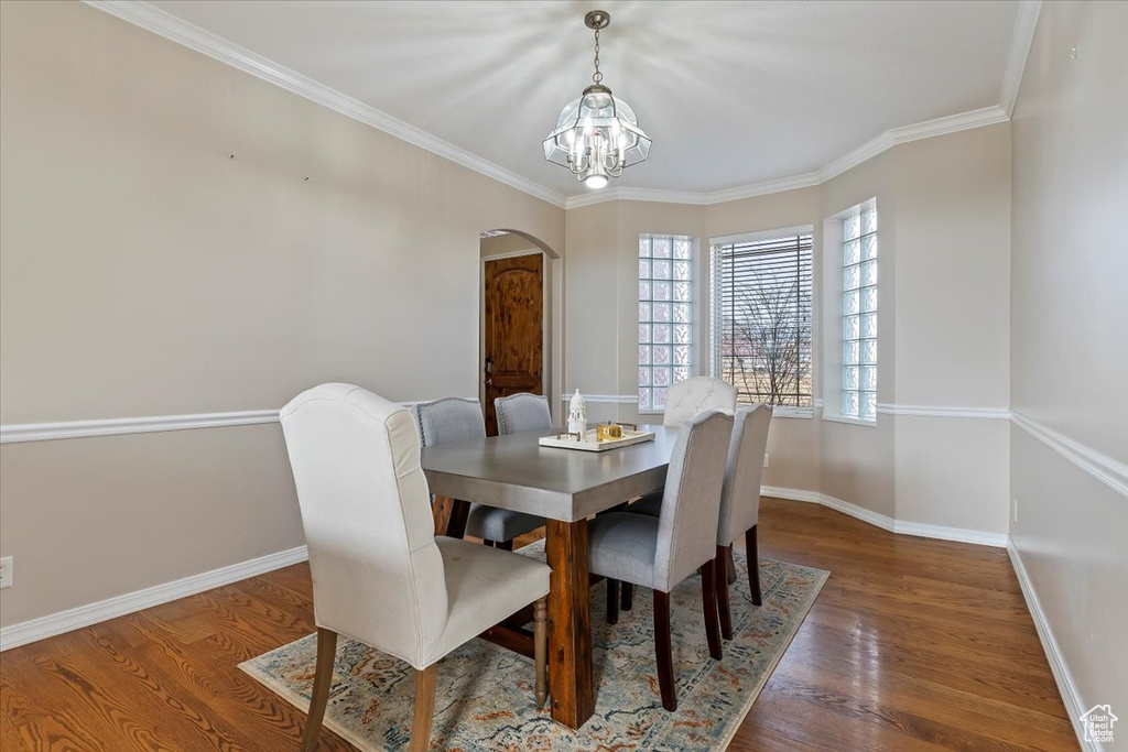 Dining area with ornamental molding, dark hardwood / wood-style flooring, and an inviting chandelier