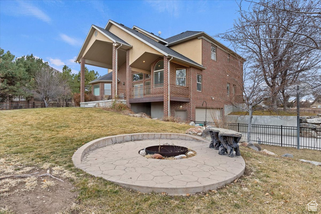 Back of property featuring a garage, a fire pit, and a yard