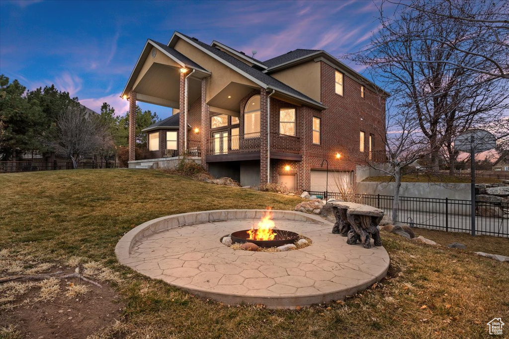 Back house at dusk featuring a fire pit and a yard