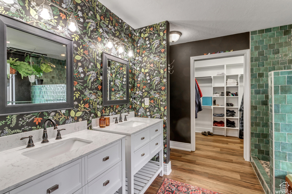 Bathroom featuring wood-type flooring, tile walls, and dual bowl vanity
