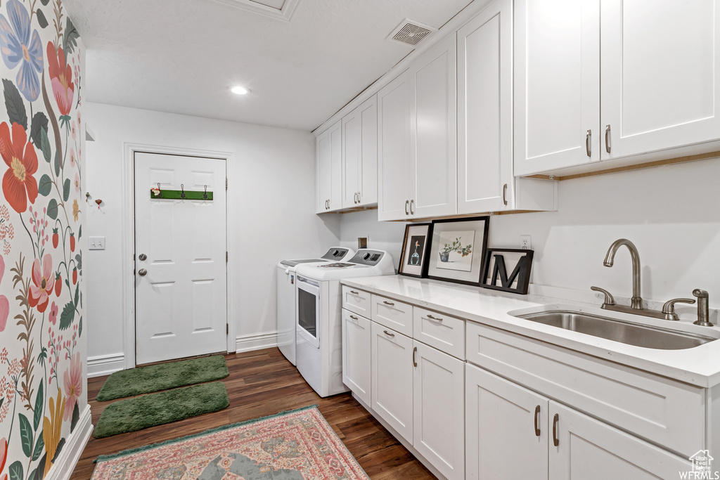 Laundry room with dark hardwood / wood-style floors, cabinets, washing machine and dryer, and sink