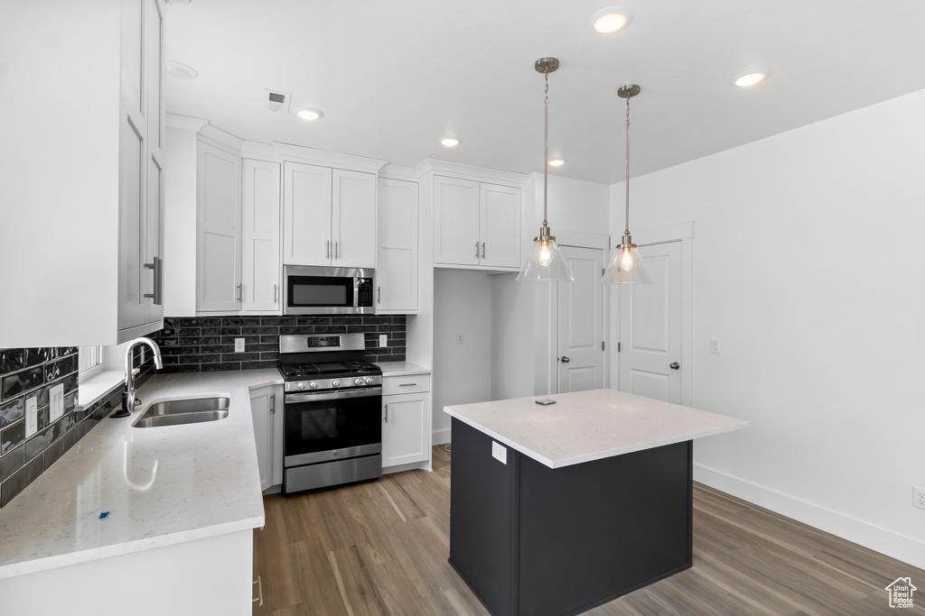 Kitchen featuring white cabinets, dark hardwood / wood-style flooring, a center island, and appliances with stainless steel finishes