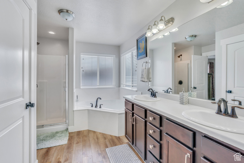 Bathroom featuring wood-type flooring, double sink vanity, and plus walk in shower