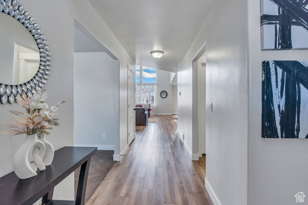Corridor with light hardwood / wood-style floors and a textured ceiling