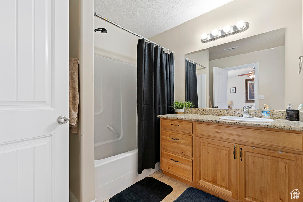 Bathroom with vanity, a textured ceiling, tile floors, ceiling fan, and shower / tub combo