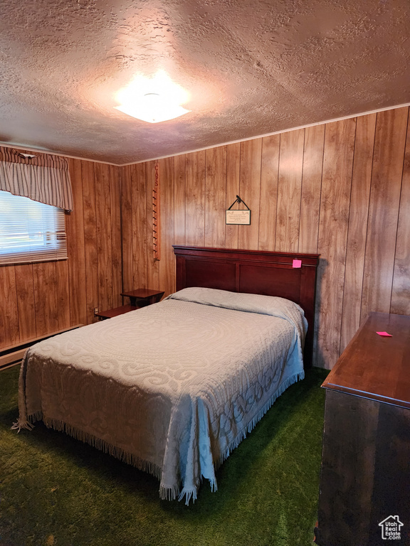 Carpeted bedroom featuring wood walls and a textured ceiling