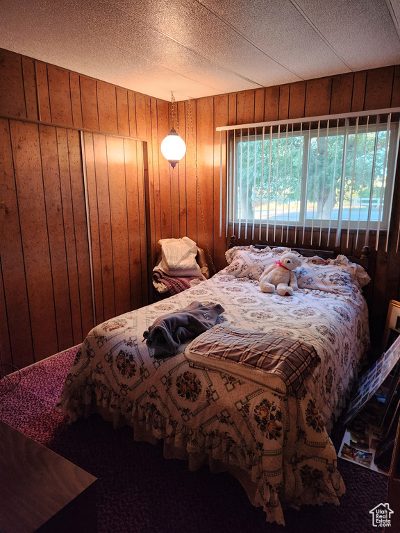 Carpeted bedroom with wooden walls and a textured ceiling