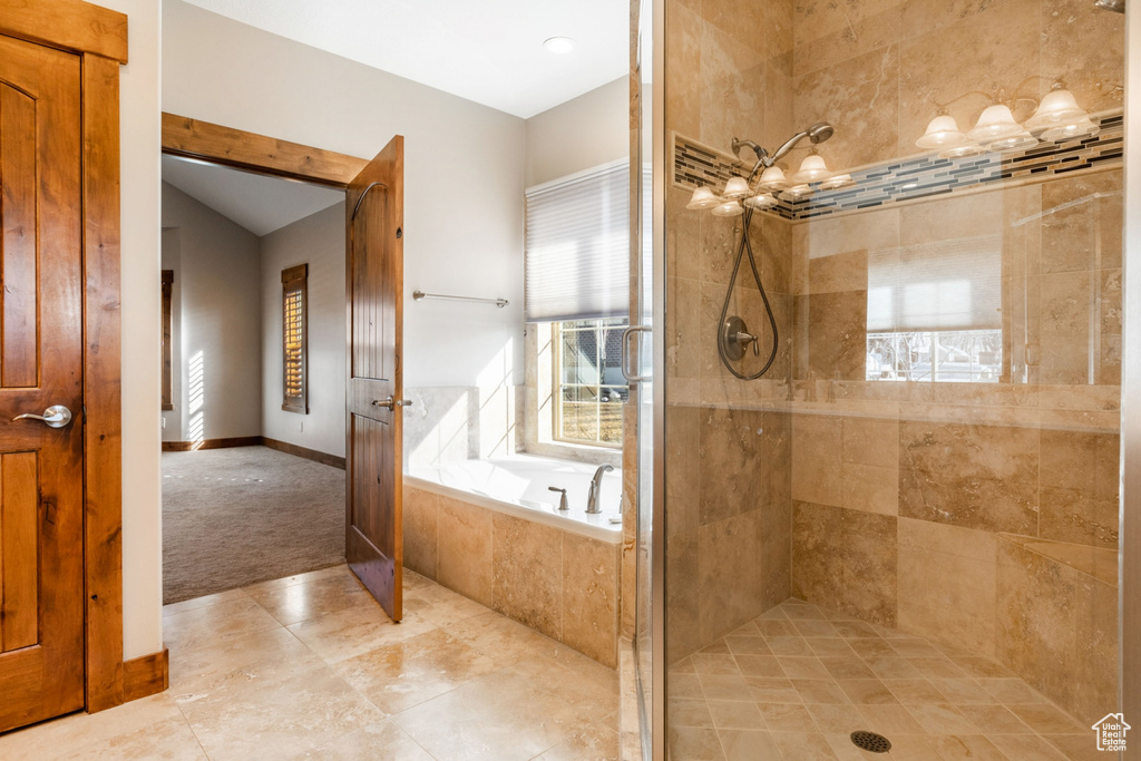 Bathroom featuring a notable chandelier, a healthy amount of sunlight, separate shower and tub, and tile flooring