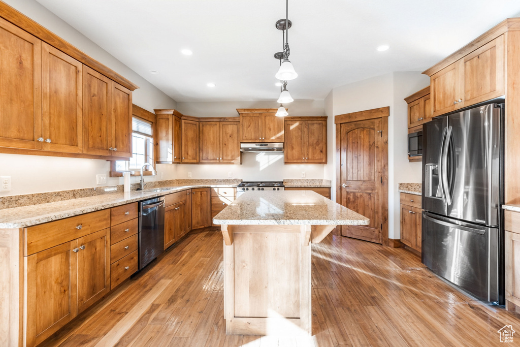 Kitchen featuring extractor fan, stainless steel appliances, light hardwood / wood-style floors, pendant lighting, and a center island