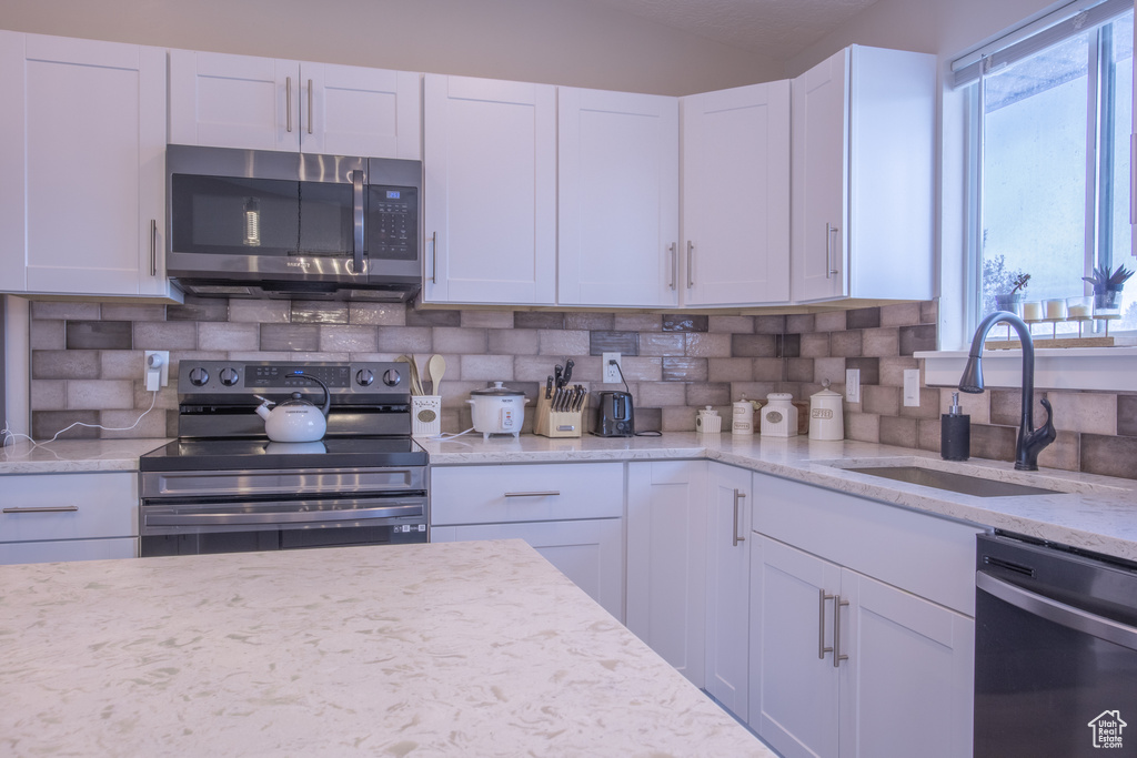 Kitchen featuring white cabinets, range with electric stovetop, and dishwashing machine