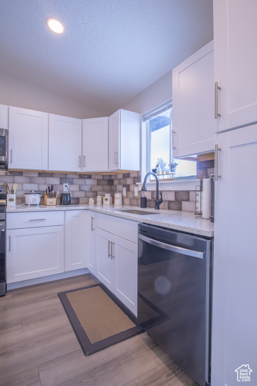 Kitchen featuring white cabinets, light hardwood / wood-style flooring, stainless steel appliances, sink, and tasteful backsplash