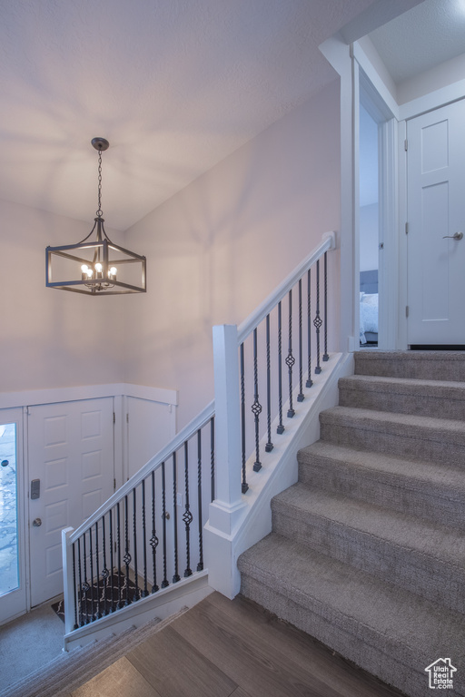 Stairway with a notable chandelier and hardwood / wood-style flooring