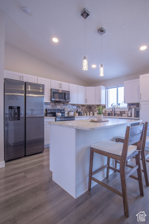 Kitchen with pendant lighting, white cabinets, and stainless steel appliances