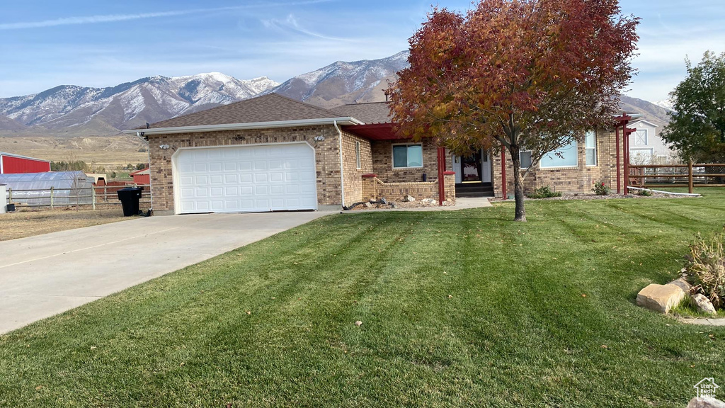 View of front of property featuring a garage, a front lawn, and a mountain view