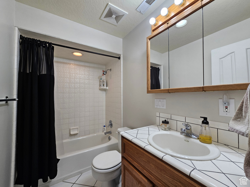 Full bathroom featuring shower / bath combination with curtain, toilet, vanity, and tile floors