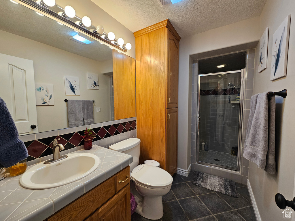 Bathroom with vanity, toilet, an enclosed shower, tasteful backsplash, and tile flooring
