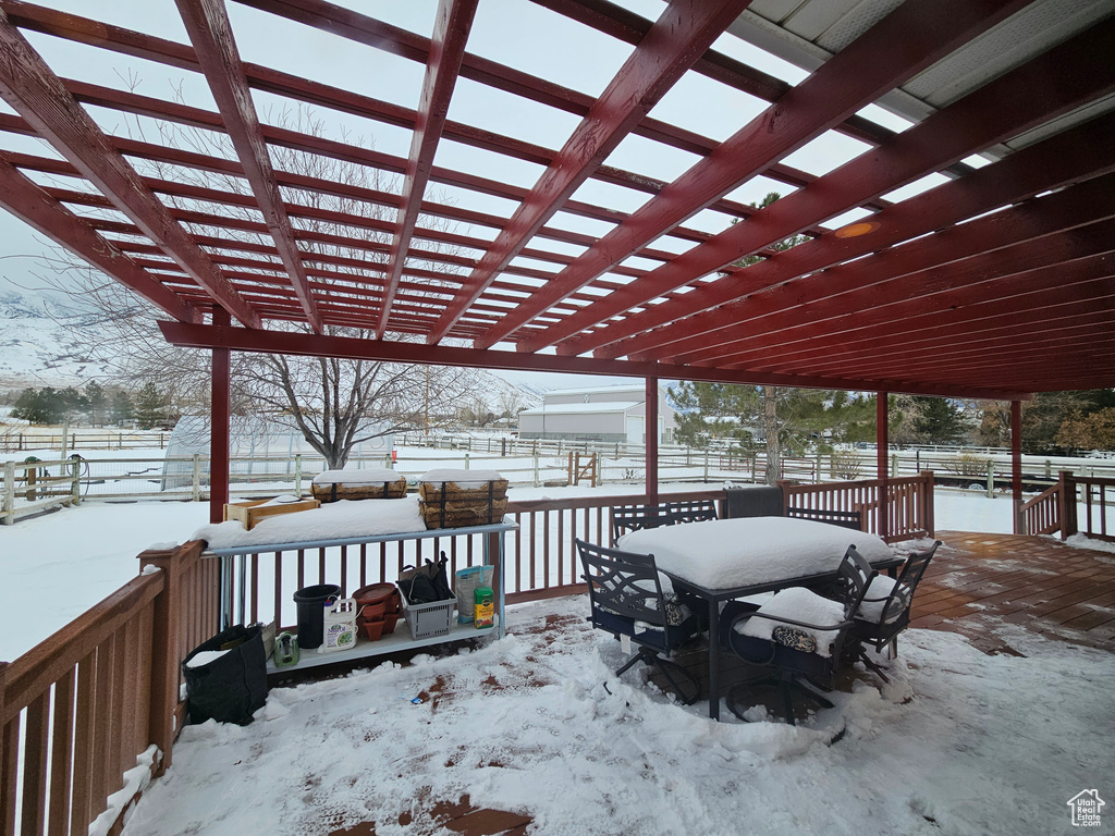 Snow covered patio with a pergola and a wooden deck