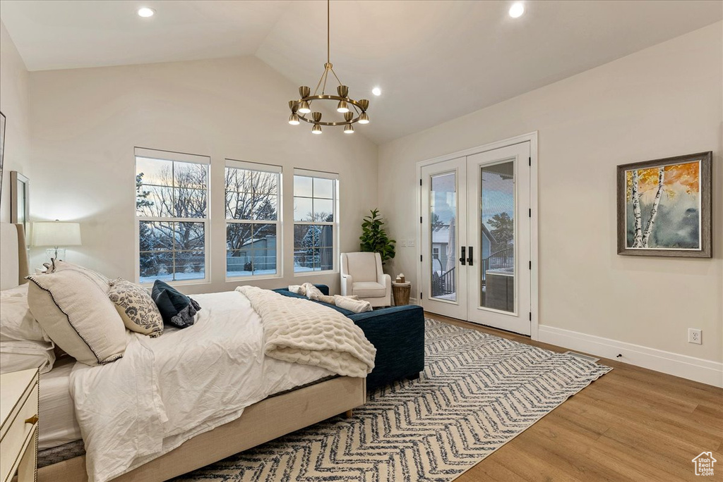 Bedroom featuring an inviting chandelier, french doors, access to exterior, vaulted ceiling, and light wood-type flooring