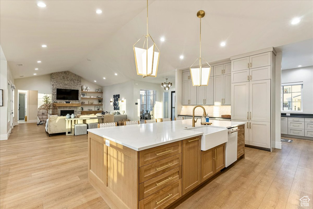 Kitchen featuring a center island with sink, sink, light hardwood / wood-style floors, and a fireplace