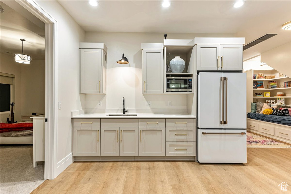 Kitchen featuring sink, stainless steel microwave, high end fridge, and light wood-type flooring