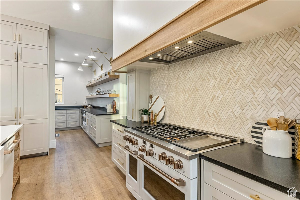 Kitchen featuring range with two ovens, dishwasher, white cabinets, light hardwood / wood-style floors, and tasteful backsplash