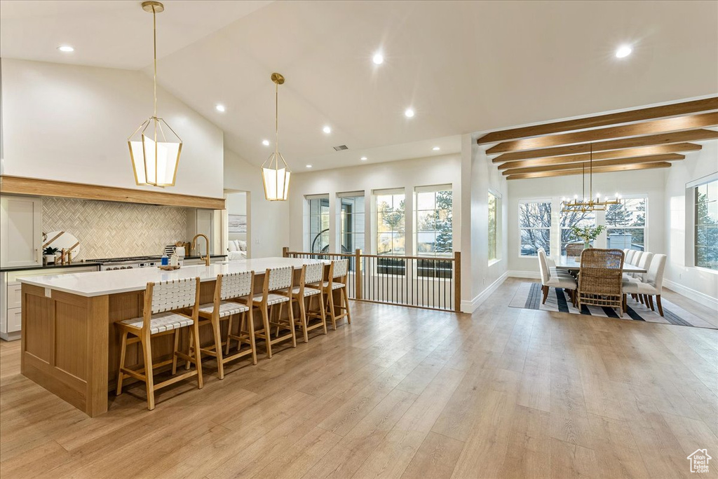 Kitchen featuring a chandelier, light hardwood / wood-style flooring, an island with sink, and plenty of natural light