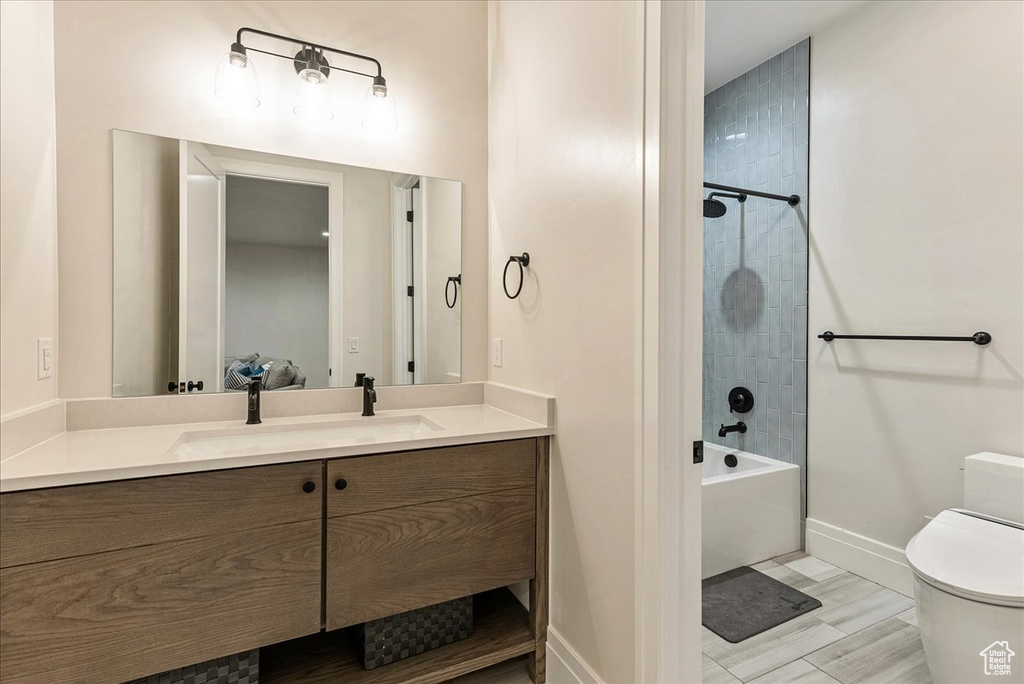 Full bathroom with tile floors, tiled shower / bath, toilet, and vanity