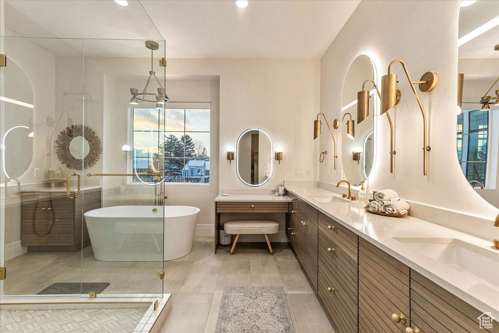 Bathroom featuring dual sinks, vanity with extensive cabinet space, tile flooring, and shower with separate bathtub