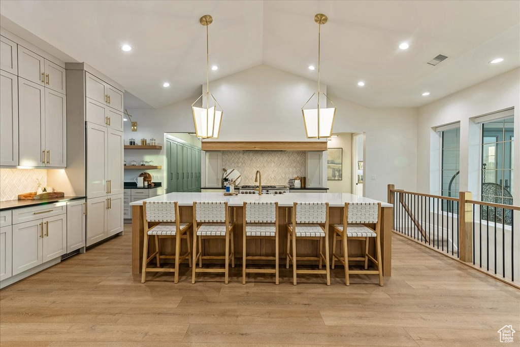 Kitchen featuring a kitchen island with sink, light hardwood / wood-style floors, and a kitchen bar