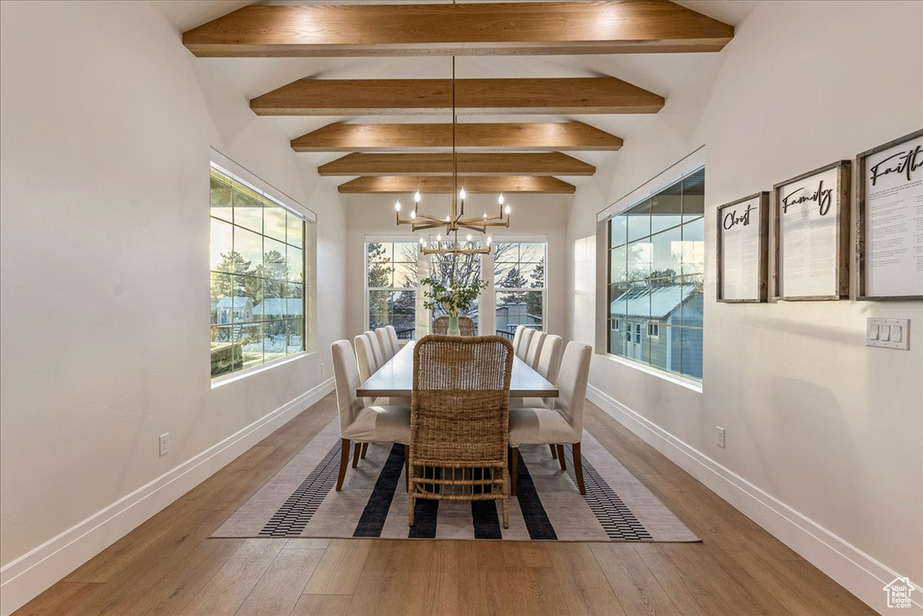 Dining space with a chandelier, vaulted ceiling with beams, and light hardwood / wood-style floors