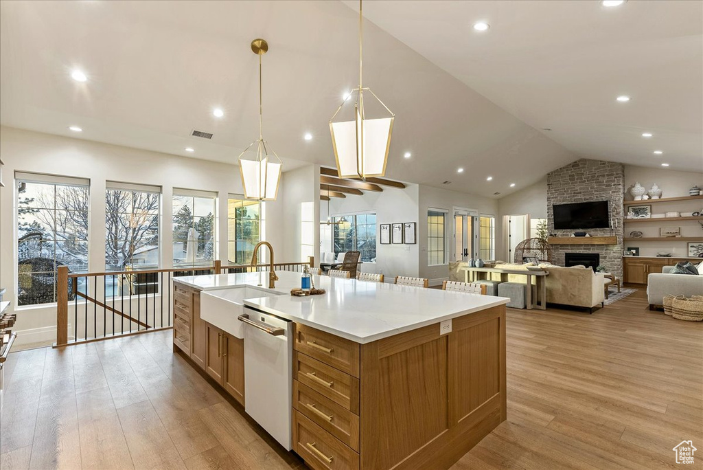 Kitchen featuring a fireplace, hanging light fixtures, light hardwood / wood-style floors, white dishwasher, and sink