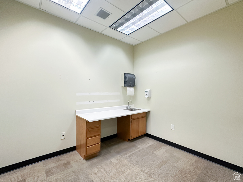 Unfurnished office with a drop ceiling, sink, and light carpet
