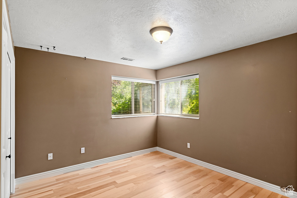 Spare room with light hardwood / wood-style floors and a textured ceiling