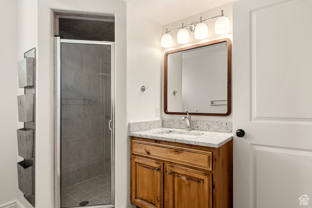 Bathroom featuring a shower with shower door and vanity