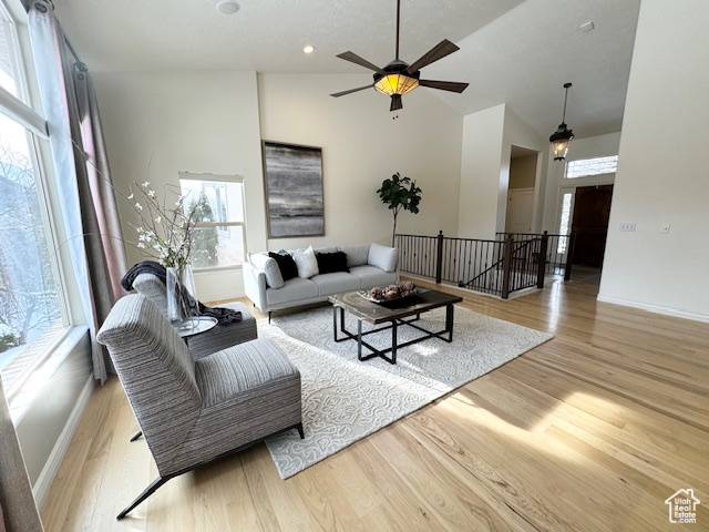 Living room with light hardwood / wood-style floors, high vaulted ceiling, and ceiling fan