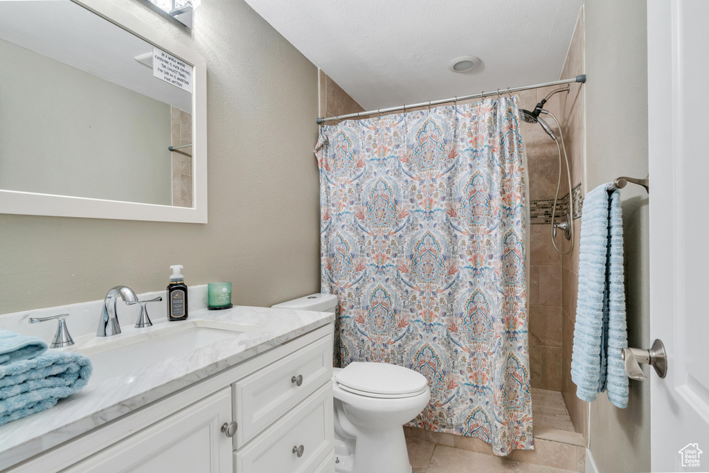 Bathroom featuring tile floors, large vanity, toilet, and a shower with shower curtain