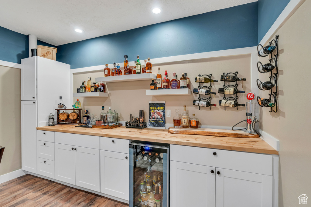 Bar featuring light hardwood / wood-style flooring, white cabinetry, wine cooler, and wood counters