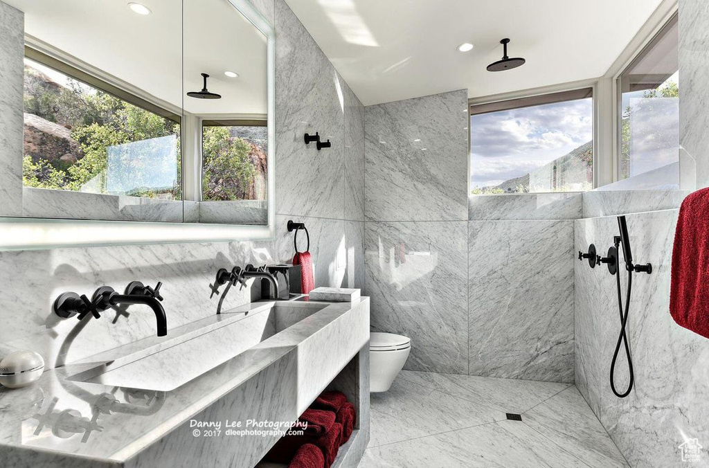 Bathroom featuring oversized vanity, toilet, tile floors, tile walls, and tiled shower