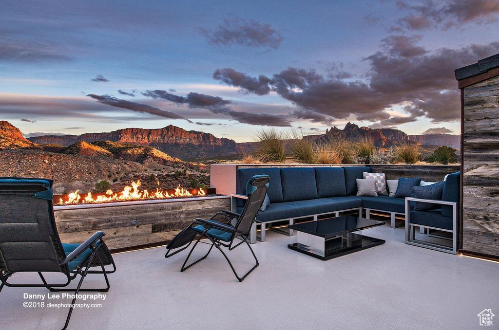 Patio terrace at dusk with an outdoor hangout area and a mountain view