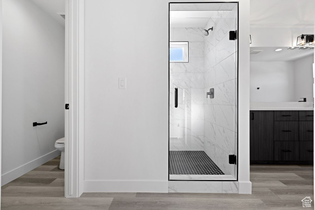 Bathroom featuring a shower with shower door, toilet, vanity, and hardwood / wood-style flooring