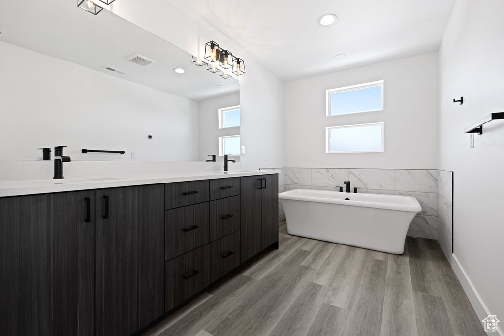 Bathroom featuring a bathing tub, double sink vanity, and hardwood / wood-style flooring