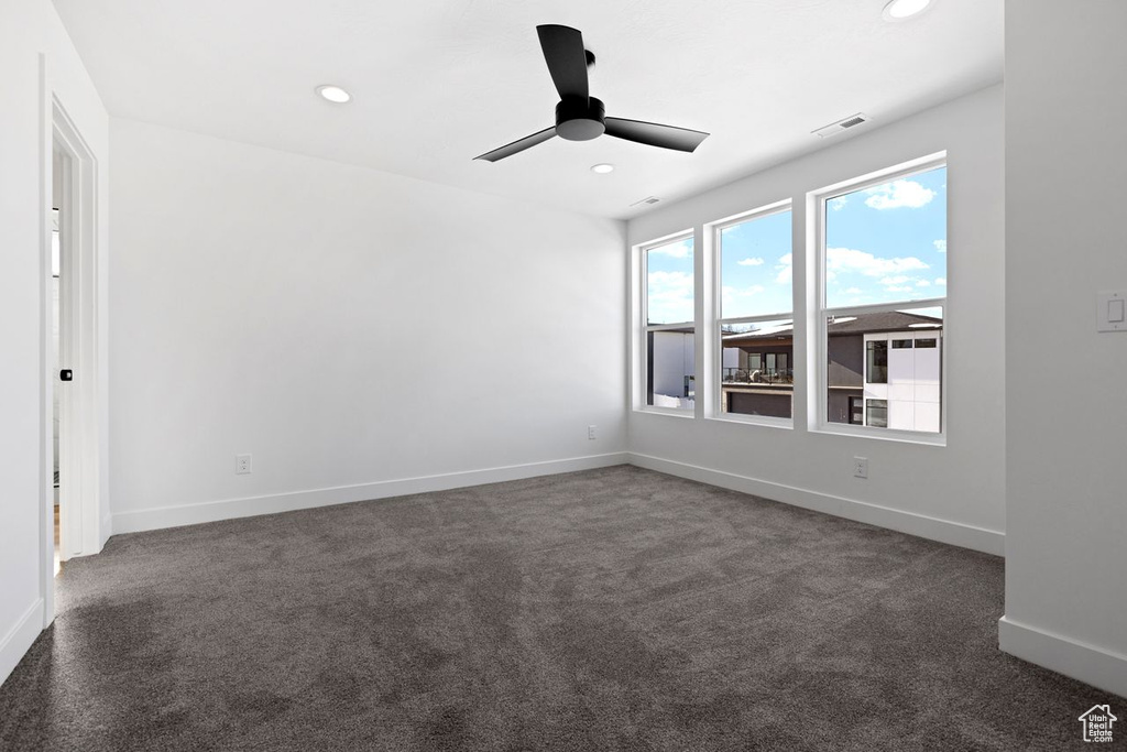 Unfurnished room featuring dark carpet and ceiling fan